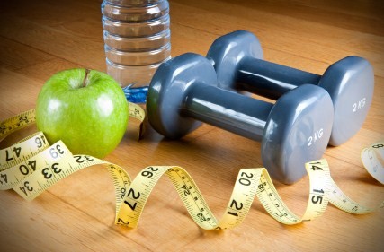 A selection of apples, dumbbells, water and a tape measure.