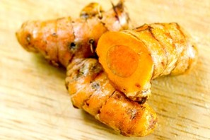 2 fresh pieces of turmeric on a wooden board.