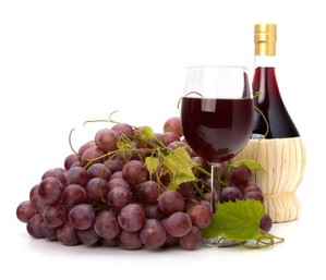 A bunch of red grapes, a glass of red wine and a bottle of red wine.