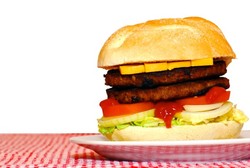 A double cheeseburger on a red and white tablecloth.