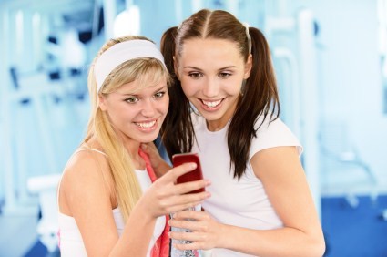 2 women in a gym looking at a mobile phone.