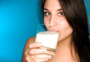 A girl drinking milk on a blue background.