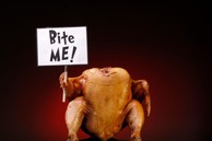 A cooked turkey holding a sign saying "Bite Me!"