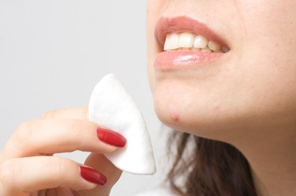 A woman wiping a spot on her chin.