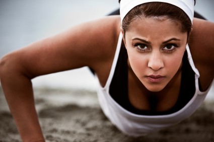 A woman doing a pressup on a beach.