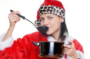 A woman cooking and tasting soup in a Christmas outfit.