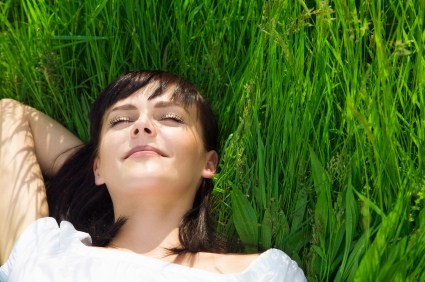 A woman relaxing lying on the grass.