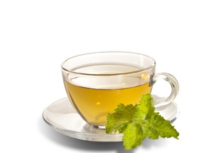 A cup of green tea on a saucer with a green leaf.