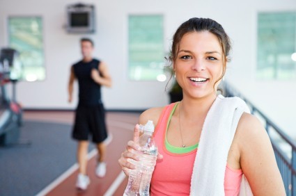 A woman in the gym drinking a bottle of water.