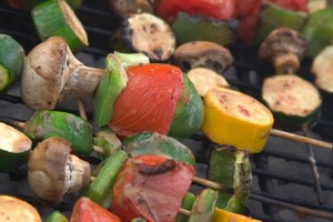 A selection of mixed vegetable kebabs on a grill.
