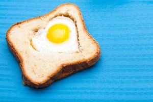 A heart shaped egg within a slice of toast.