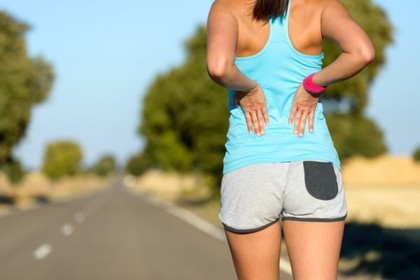 A woman holding her lower back.