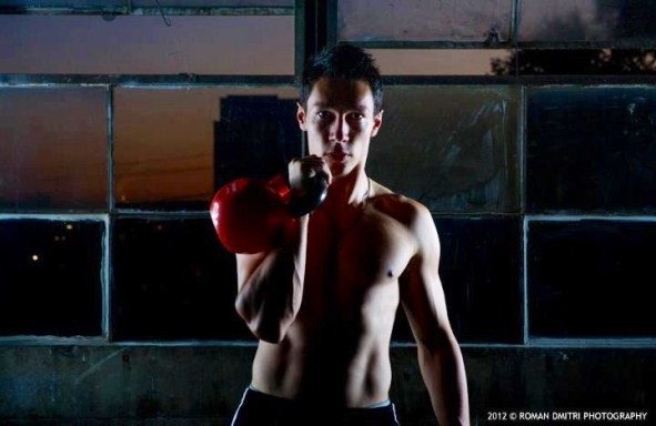 Srdjan Popovic curling a kettlebell with his right arm.
