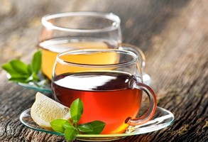 2 glass cups of black and green tea with a lemon slice.