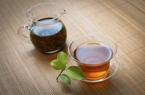 A glass pot and glass cup of black tea.