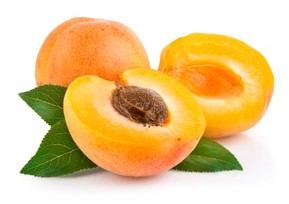A whole and chopped apricot on a white background.