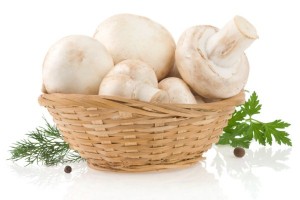 A basket of mushrooms surrounded by green leaves.