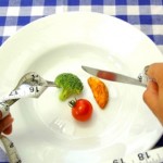 A person eating vegetables with a tape measure wrapped around their hands.